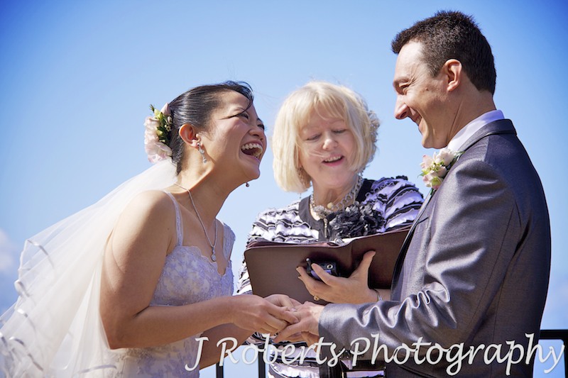 Bride laughing while putting the ring on grooms finger - wedding photography sydney